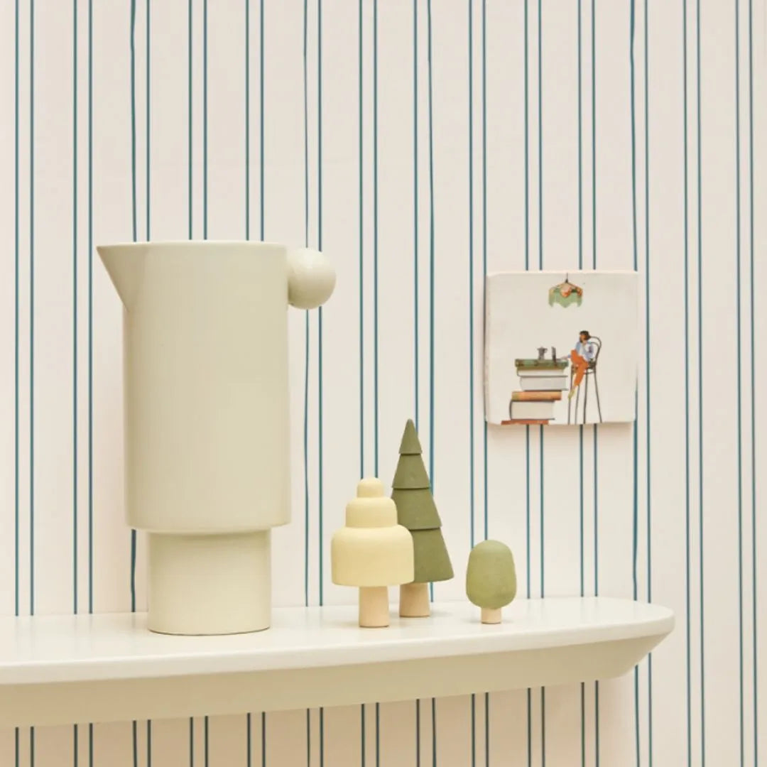 Gestreept petrol behang van Bibelotte achter een wandtafel met houten boompjes