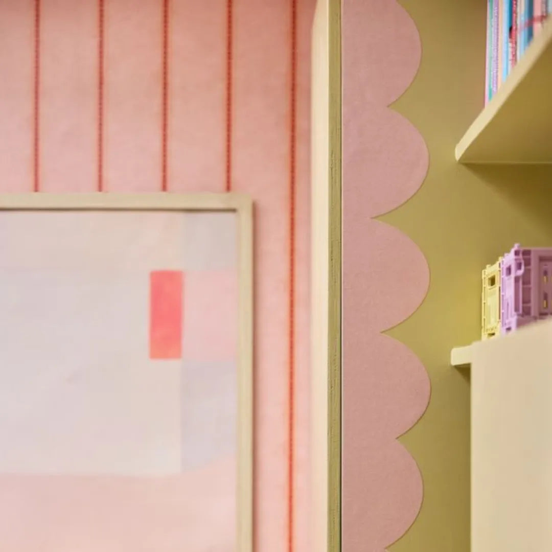 Roze gestreepte kinderkamerwand met een golvende behangrand van Bibelotte langs de kastrand