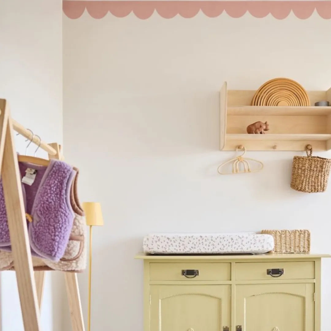Babykamer met witte muren en een roze golvende behangrand van Bibelotte langs het plafond